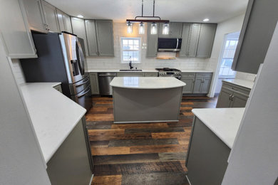 Kitchen - large contemporary u-shaped laminate floor and brown floor kitchen idea in Other with an undermount sink, recessed-panel cabinets, gray cabinets, quartz countertops, white backsplash, ceramic backsplash, stainless steel appliances, two islands and white countertops