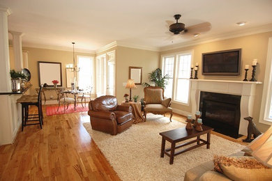Example of a huge classic open concept medium tone wood floor living room design in Tampa with beige walls, a standard fireplace, a wood fireplace surround and a wall-mounted tv