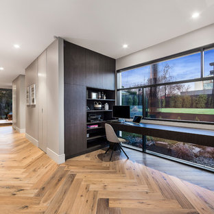 Design ideas for a small modern study in Melbourne with multi-coloured walls, light hardwood flooring, no fireplace, a built-in desk and brown floors.