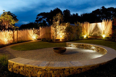 Large beach style backyard full sun formal garden in Melbourne with a fire feature and gravel.
