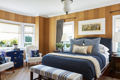 This is an example of a large beach style guest bedroom in Boston with multi-coloured walls, medium hardwood floors, a standard fireplace, a wood fireplace surround and brown floor.