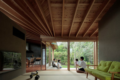Imagen de salón para visitas abierto pequeño con tatami, televisor colgado en la pared, suelo marrón, vigas vistas, papel pintado y paredes verdes