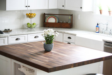 Transitional l-shaped medium tone wood floor open concept kitchen photo in Richmond with a farmhouse sink, shaker cabinets, white cabinets, granite countertops, white backsplash, subway tile backsplash, stainless steel appliances and an island
