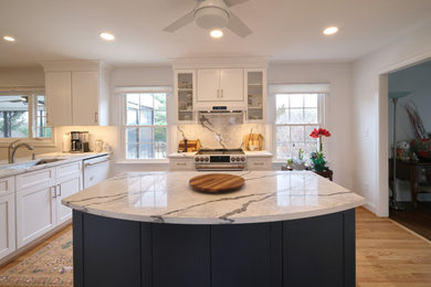 Inspiration for a mid-sized transitional l-shaped light wood floor and brown floor open concept kitchen remodel in Baltimore with an undermount sink, shaker cabinets, white cabinets, quartz countertops, gray backsplash, quartz backsplash, white appliances, an island and gray countertops