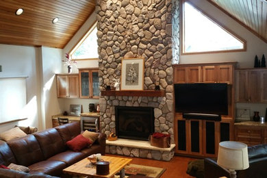 Huge loft-style living room library photo in Minneapolis with a wood stove, a stone fireplace and a media wall