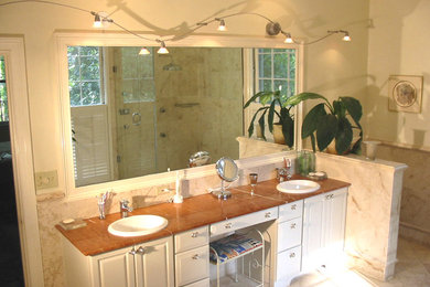 This is an example of an eclectic bathroom in Atlanta with raised-panel cabinets, white cabinets, marble benchtops, beige tile and stone tile.