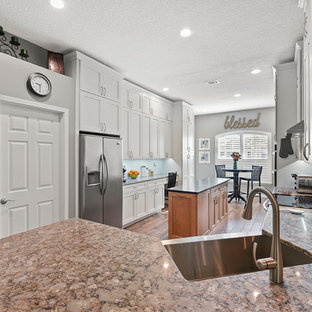 Large contemporary kitchen pantry designs - Kitchen pantry - large contemporary u-shaped brown floor and porcelain floor kitchen pantry idea in Jacksonville with a farmhouse sink, shaker cabinets, white cabinets, quartzite countertops, white backsplash, porcelain backsplash, stainless steel appliances and an island