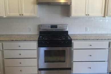 Inspiration for a mid-sized transitional single-wall dark wood floor and brown floor enclosed kitchen remodel in Other with an undermount sink, recessed-panel cabinets, white cabinets, granite countertops, white backsplash, subway tile backsplash, stainless steel appliances and no island