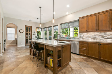 Inspiration for a large transitional u-shaped travertine floor and brown floor kitchen remodel in San Diego with an undermount sink, recessed-panel cabinets, medium tone wood cabinets, quartzite countertops, multicolored backsplash, stainless steel appliances, an island and gray countertops