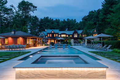This is an example of an expansive traditional side yard rectangular pool in Boston with a water feature.