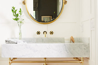 Powder room - mid-sized transitional medium tone wood floor and brown floor powder room idea in Orange County with white walls, an undermount sink, marble countertops, white countertops and a built-in vanity