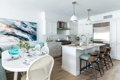 Eat-in kitchen - mid-sized contemporary u-shaped medium tone wood floor eat-in kitchen idea in New York with an undermount sink, shaker cabinets, white cabinets, granite countertops, white backsplash, subway tile backsplash, stainless steel appliances, an island and white countertops