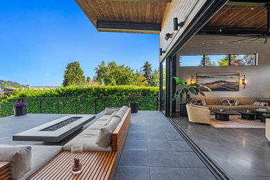 Example of a large urban backyard concrete paver patio design in Seattle with a fire pit and a roof extension
