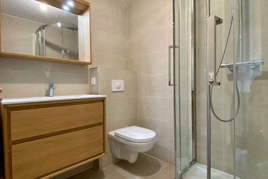 Réalisation d'une salle de bain principale tradition en bois clair de taille moyenne avec un placard avec porte à panneau encastré, une douche d'angle, WC suspendus, un carrelage beige, des dalles de pierre, un mur beige, carreaux de ciment au sol, une grande vasque, un plan de toilette en surface solide, un sol beige, une cabine de douche à porte coulissante, un plan de toilette blanc, meuble simple vasque et meuble-lavabo suspendu.