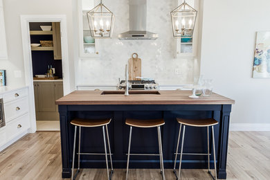 Large minimalist l-shaped medium tone wood floor and brown floor kitchen photo in Other with an undermount sink, wood countertops, white backsplash, marble backsplash, stainless steel appliances and white countertops