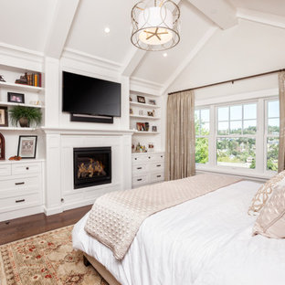 Idées déco pour une chambre parentale classique de taille moyenne avec un mur blanc, un sol en bois brun, une cheminée standard, un manteau de cheminée en bois et un sol marron.