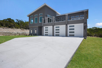 Inspiration for a large modern gray two-story stucco house exterior remodel in Austin with a shed roof and a metal roof