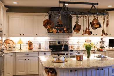 Inspiration for a country u-shaped eat-in kitchen in Wichita with an undermount sink, raised-panel cabinets, white cabinets, granite benchtops, white splashback, subway tile splashback, stainless steel appliances, medium hardwood floors, with island and brown floor.