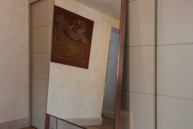 Immagine di un piccolo ingresso chic con pareti beige, parquet chiaro, una porta singola, una porta marrone, pavimento beige, soffitto ribassato, boiserie e armadio