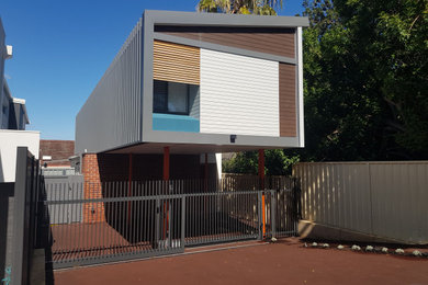 Inspiration for a small contemporary two-storey exterior in Perth with metal siding, a metal roof, a grey roof and board and batten siding.