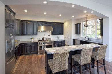 Eat-in kitchen - mid-sized contemporary u-shaped medium tone wood floor eat-in kitchen idea in Wilmington with an undermount sink, recessed-panel cabinets, dark wood cabinets, granite countertops, stainless steel appliances and an island