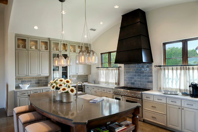 Large transitional u-shaped limestone floor open concept kitchen photo in Dallas with a farmhouse sink, raised-panel cabinets, limestone countertops, gray backsplash, subway tile backsplash, stainless steel appliances and an island