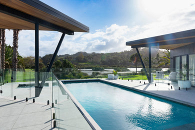 Diseño de casa de la piscina y piscina natural marinera de tamaño medio rectangular en patio trasero con adoquines de hormigón