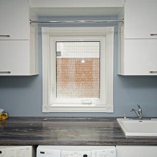 This is an example of a medium sized contemporary single-wall utility room in Other with flat-panel cabinets, white cabinets, laminate countertops, blue walls, laminate floors, brown floors and grey worktops.