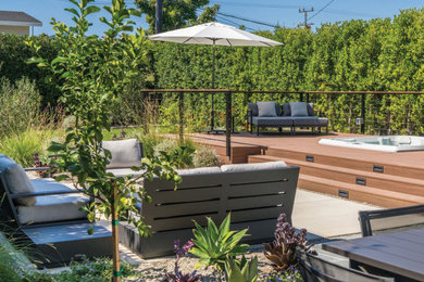 Photo of a contemporary drought-tolerant and partial sun backyard landscaping in Los Angeles with a fire pit and decking.