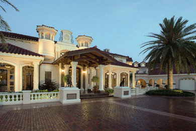 Huge tuscan beige three-story stucco exterior home photo in Los Angeles with a hip roof