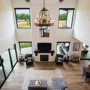 Großes, Offenes Mediterranes Wohnzimmer mit weißer Wandfarbe, braunem Holzboden, Kamin, Kaminsims aus Backstein, Wand-TV und braunem Boden in Vancouver