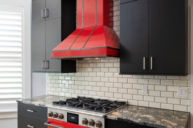 Porcelain tile and beige floor kitchen photo in Miami with a single-bowl sink, flat-panel cabinets, black cabinets, granite countertops, white backsplash, ceramic backsplash, colored appliances, an island and black countertops