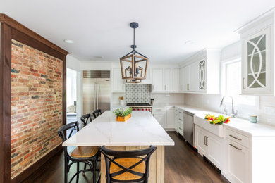 Example of a mid-sized cottage l-shaped medium tone wood floor and brown floor kitchen pantry design in New York with a farmhouse sink, recessed-panel cabinets, white cabinets, quartz countertops, white backsplash, porcelain backsplash, stainless steel appliances, an island and white countertops