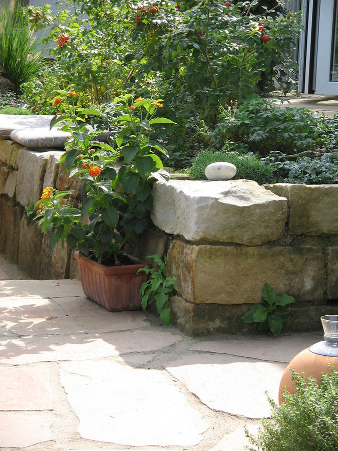 Kleine Terrasse mit Sitzmauer aus Naturstein - gartenRAUM Planungsbüro