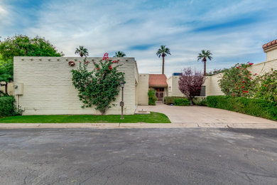 Example of a mid-sized minimalist beige one-story brick house exterior design in Phoenix with a gambrel roof and a tile roof