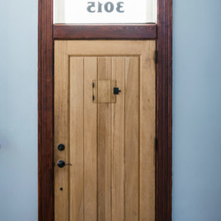 Inredning av en eklektisk mellanstor ingång och ytterdörr, med blå väggar, ljust trägolv, en pivotdörr, ljus trädörr och brunt golv