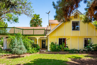Foto de fachada de casa amarilla y marrón de estilo de casa de campo de tamaño medio de dos plantas con revestimiento de madera, tejado a dos aguas y tejado de teja de madera
