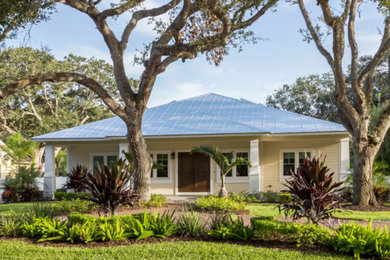 Mid-sized traditional beige one-story wood house exterior idea in Miami with a hip roof and a metal roof