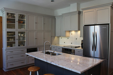Mid-sized eclectic l-shaped medium tone wood floor eat-in kitchen photo in Columbus with an undermount sink, recessed-panel cabinets, gray cabinets, granite countertops, white backsplash, ceramic backsplash, stainless steel appliances and an island