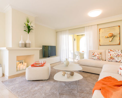 Diseño de sala de estar abierta, costera, de tamaño medio, con paredes beige, chimenea tradicional, marco de chimenea de yeso, televisor independiente y suelo beige