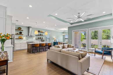 Example of a large transitional open concept light wood floor and vaulted ceiling living room design in Jacksonville with green walls