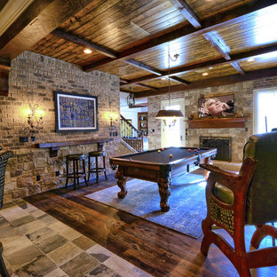 Exemple d'une grande salle de cinéma chic ouverte avec un mur marron, un sol en travertin, un téléviseur fixé au mur et un sol marron.