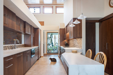 Photo of a medium sized modern galley kitchen/diner in Minneapolis with a submerged sink, flat-panel cabinets, dark wood cabinets, marble worktops, multi-coloured splashback, glass tiled splashback, stainless steel appliances, vinyl flooring, beige floors, white worktops and a wood ceiling.