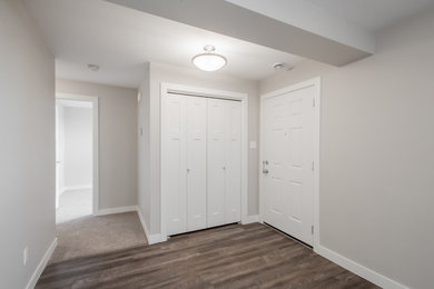 Entryway - mid-sized transitional medium tone wood floor entryway idea in Calgary with gray walls and a white front door
