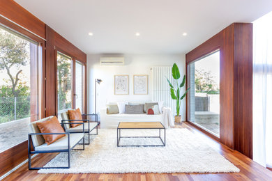 Ejemplo de salón abierto moderno de tamaño medio con paredes blancas y suelo de madera en tonos medios