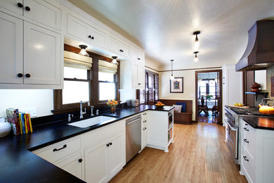 Inspiration for a galley medium tone wood floor enclosed kitchen remodel in Los Angeles with a farmhouse sink, shaker cabinets, white cabinets, soapstone countertops, green backsplash, porcelain backsplash and stainless steel appliances