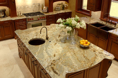 Open concept kitchen - large traditional l-shaped ceramic tile open concept kitchen idea in Milwaukee with a farmhouse sink, raised-panel cabinets, medium tone wood cabinets, beige backsplash, stone tile backsplash, paneled appliances, an island and granite countertops