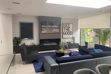 Imagen de cine en casa minimalista de tamaño medio con paredes blancas, suelo de mármol, televisor colgado en la pared y suelo gris