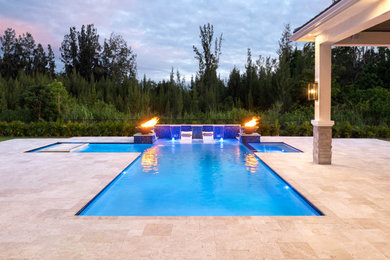 Photo of a large modern backyard custom-shaped pool in Miami with a water feature and natural stone pavers.