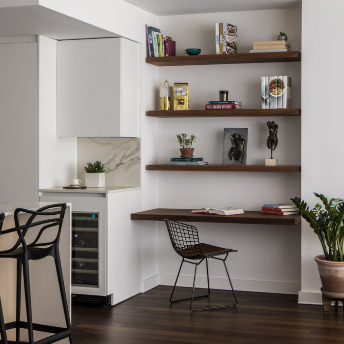 This charming home office nook is the perfect blend of style and functionality, seamlessly integrated into the kitchen remodel. With warm, floating walnut wood shelves above a streamlined desk, it off